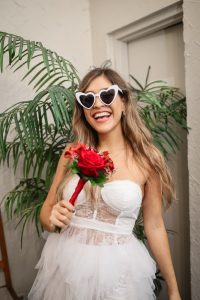 A playful Las Vegas bride in her wedding dress rental & heart sunglasses.